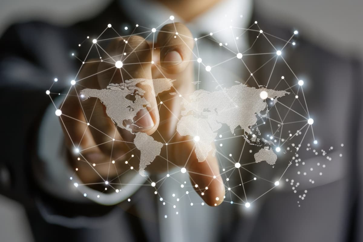 Hand with glowing world map and connected nodes — symbol of international connections